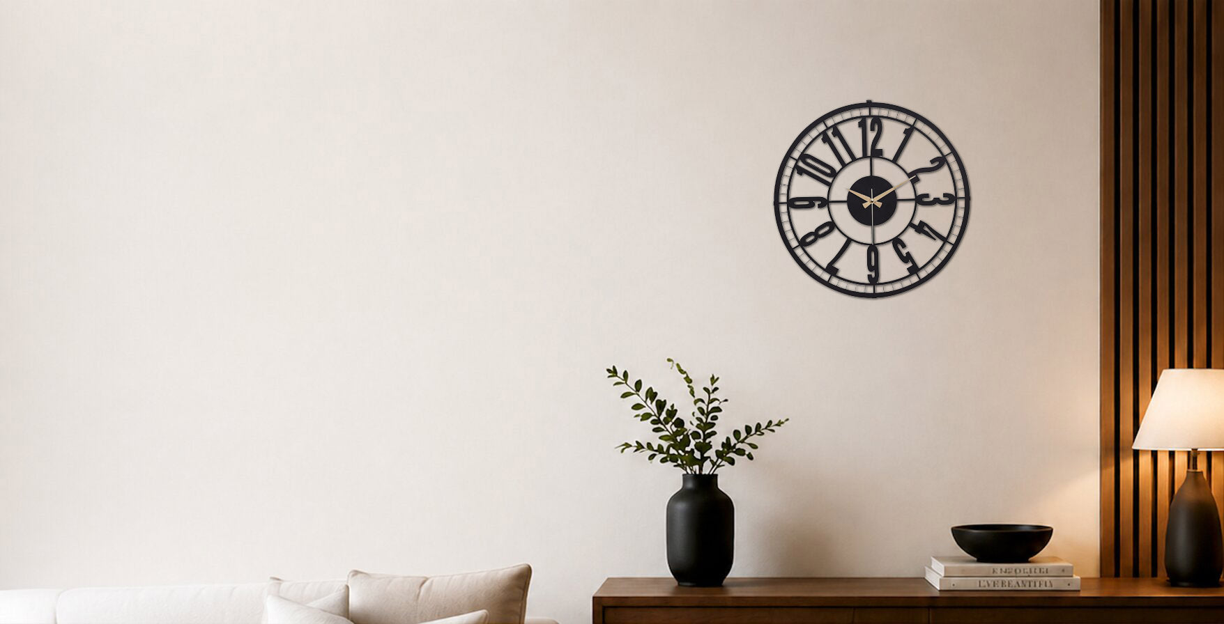 Decorative wall clock on a white wall with a plant and lamp in the foreground.